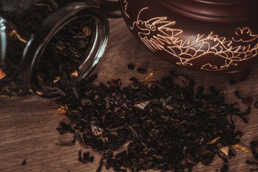 Asian teapot with dragon on stand and jar with scattering of fruit tea