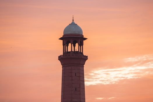 Minaret tower of a mosque calling for prayers in fiery sunset sky