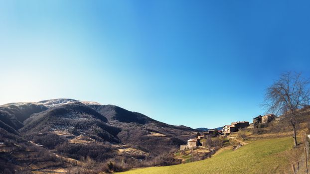 panoramic view of an old town on the slope of the valley facing the mountains with blue clear sky, copy space for text