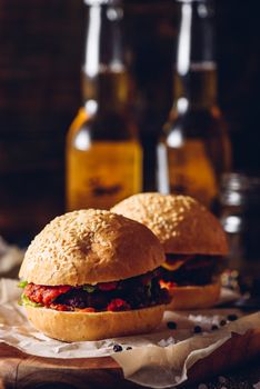 Two Cheeseburger on Cutting Board and Few Bottle of Beer on Background. Vertical Orientation.