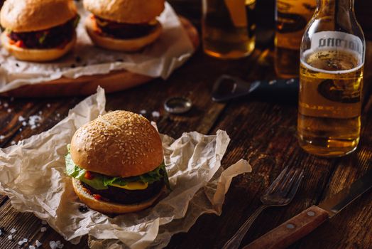 Homemade Hamburger with Bottle of Beer on Dark Wooden Table.
