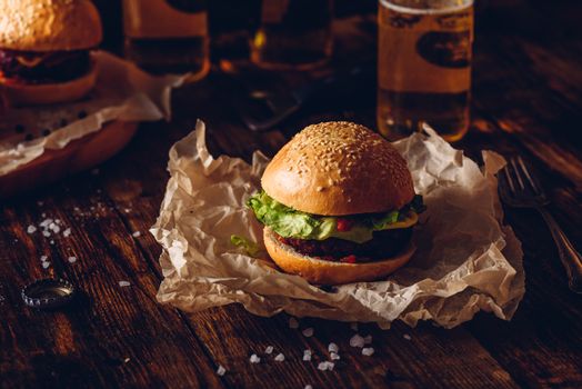 Burger on Kraft Paper. Bottles of Lager on Background.