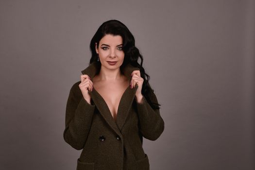 Studio portrait of a woman in classic coat posing on a gray background. Set of retro suitcases and hand bag. The concept of  tourism, recreation and travel advertising for designers with copy space.