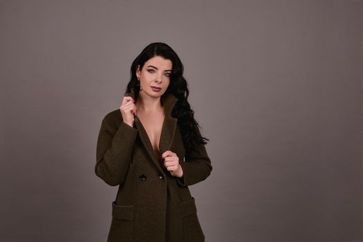 Studio portrait of a woman in classic coat posing on a gray background. Set of retro suitcases and hand bag. The concept of  tourism, recreation and travel advertising for designers with copy space.