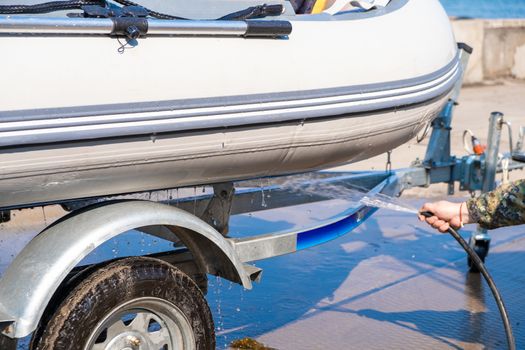 A man washes a rubber hose boat after going to sea. Drops of water scatter from the boat.