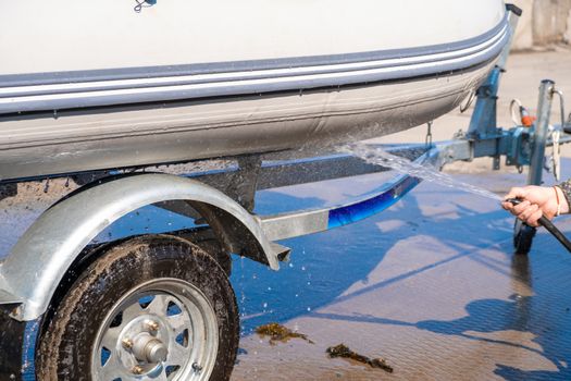 A man washes a rubber hose boat after going to sea. Drops of water scatter from the boat.