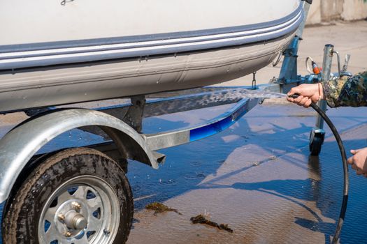 A man washes a rubber hose boat after going to sea. Drops of water scatter from the boat.