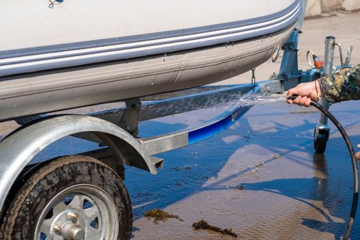 A man washes a rubber hose boat after going to sea. Drops of water scatter from the boat.