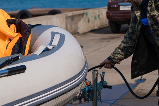 A man washes a rubber hose boat after going to sea. Drops of water scatter from the boat.