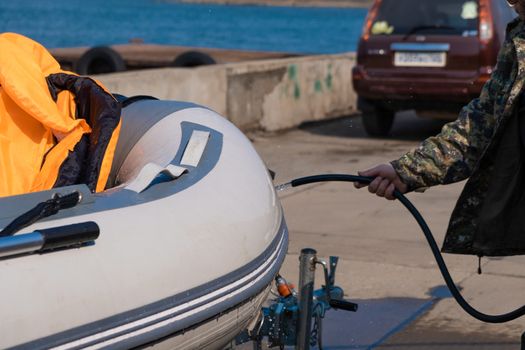 A man washes a rubber hose boat after going to sea. Drops of water scatter from the boat.