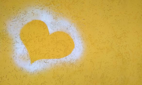 Silhouette of the heart on the yellow plaster wall. Close-up.