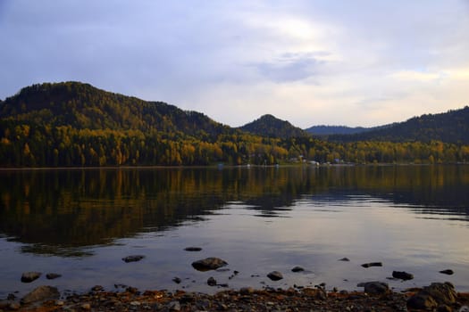 East rocky shore of Lake Teletskoye, cliffs covered with a beautiful forest. The picture was taken on an autumn day, with natural light.