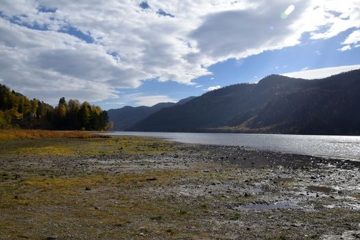 East rocky shore of Lake Teletskoye, cliffs covered with a beautiful forest. The picture was taken on an autumn day, with natural light.