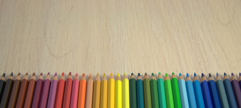 A set of colored pencils laid out in a row on the color spectrum. Close up.
