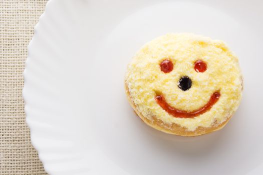 Smiley donut on a white plate, donut with white background