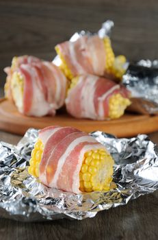 Corn wrapped with a strip of bacon, prepared for baking in foil. The recipe is suitable for grilling, barbecuing, baking in the oven.
