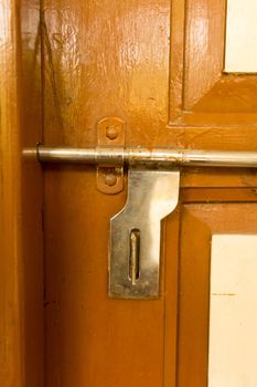 Closeup front view exterior rusty rough old brown wooden door handle of iron metal frame with in grungy style and good texture of a full closed door of a domestic living room. Architecture background.