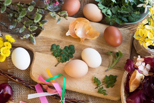 Preparation of Easter eggs for dying with onion peels: eggs, onion peels, and fresh herbs on a table