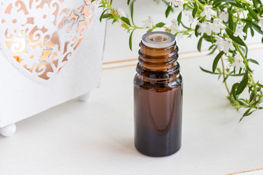 A bottle of mountain savory essential oil with fresh blooming Satureja montana