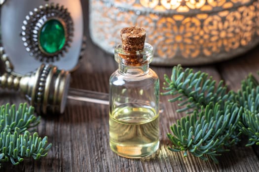A bottle of essential oil with fresh fir branches