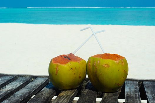 Tropical fresh coconut cocktail on white beach. Two coconut drinks on luxury tropical resort in Maldives island beach with  sea background.