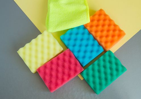 A set of multi-colored sponges and rags for cleaning and cleanliness on a gray background, the concept of outsourcing cleaning company, top View, flat lay.