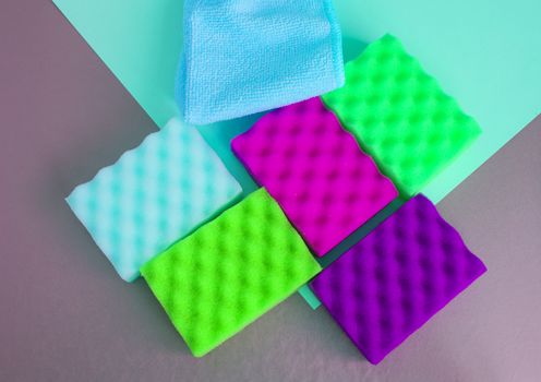 A set of multi-colored sponges and rags for cleaning and cleanliness on a gray background, the concept of outsourcing cleaning company, top View, flat lay.