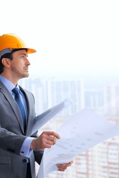 Architecture, construction business and building - smiling architect or businessman in yellow hardhat and suit with blueprint by the window