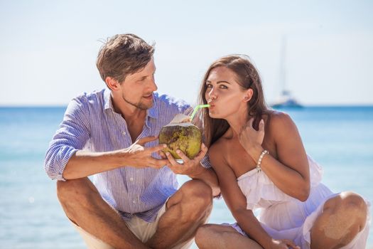 Young couple enjoying their time drinking a coconut cocktail on beach