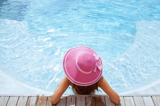 Beautiful woman relaxing at swimming pool at tourist resort