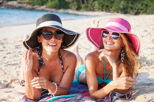 Beautiful young women in sunhats laying on beach