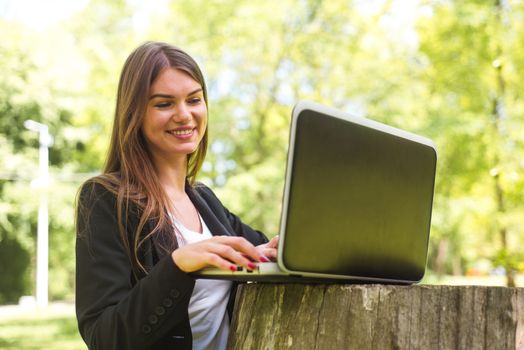 Beautiful business woman in suit using laptop computer in the park