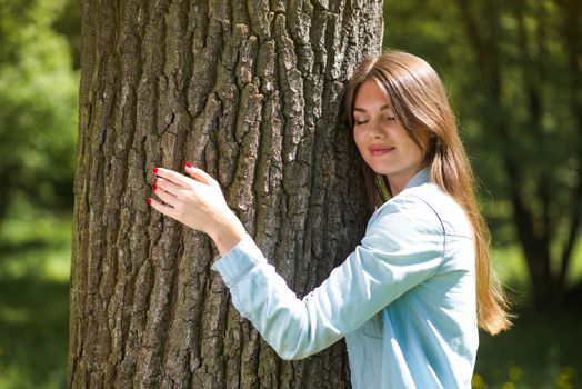 Young woman hugging a big tree, love nature concept