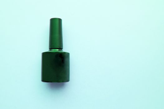 Clean black nail Polish bottle on blue background, copy space, place for your text.