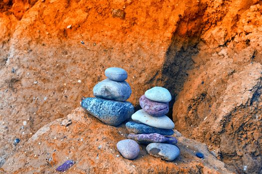 Stones stacked on top of each other on the beach in the background the cliff