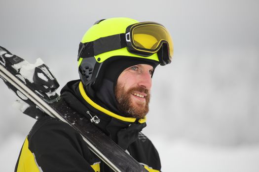 Portrait of a happy male skier in the alps with ski on shoulder