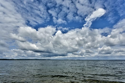 gray and white cumulonimbus clouds against the blue sky over the lake