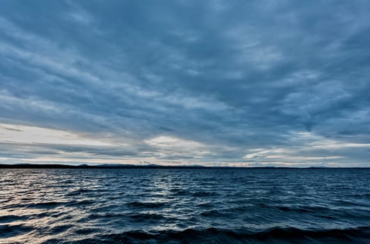 dark blue evening cloudy sky over the lake, wind, waves, heavy Shine of water