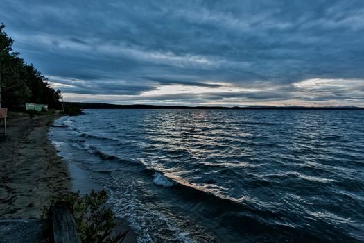 dark blue evening cloudy sky over the lake, wind, waves, heavy Shine of water