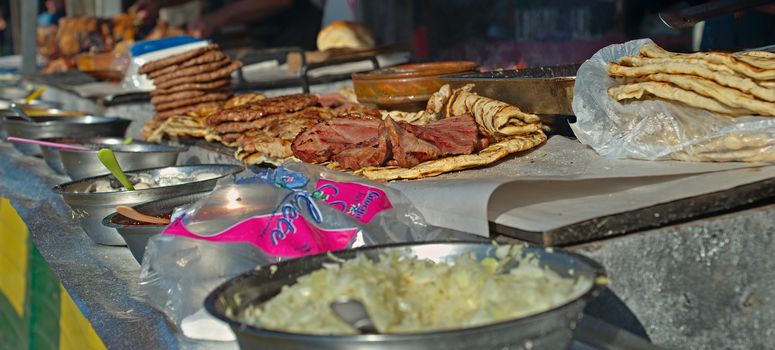 Barbeque stand with bunch of different prepared meats, closeup