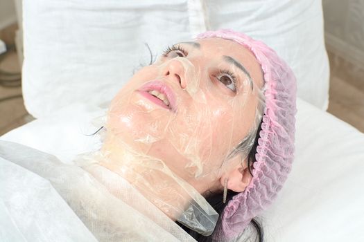 Young woman in beauty salon doing peeling and facial cleansing procedure. Cosmetic multifunctional device. Ultrasound procedure. Medical equipment healthcare. Face professional massage.