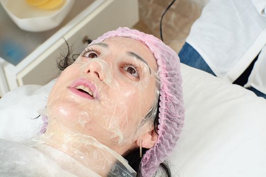 Young woman in beauty salon doing peeling and facial cleansing procedure. Cosmetic multifunctional device. Ultrasound procedure. Medical equipment healthcare. Face professional massage.