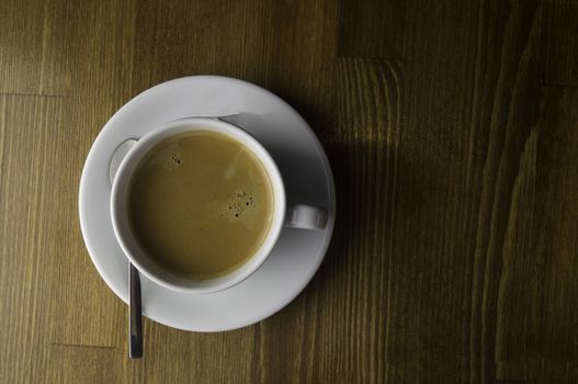 a cup of coffee and spoon placed on a brown table