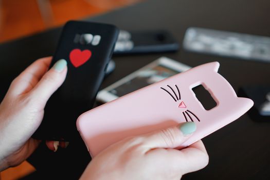 Hands holding colorful smartphone cases. Choose between a black and pink smartphone case