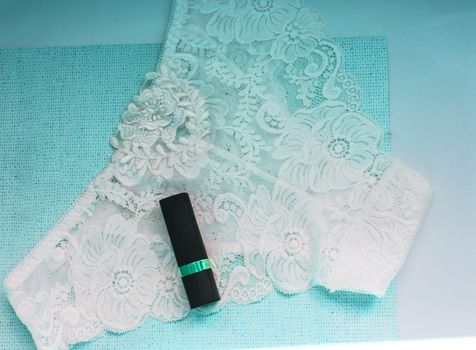 Shopping on site, and the concept of fashion. Lace glamorous white sexy panties and lipstick, accessories for women, top view, flat. Blue tinted effect