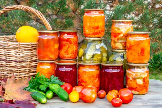 Several homemade jars of canned vegetables and fresh vegetables on a wooden table - image.
