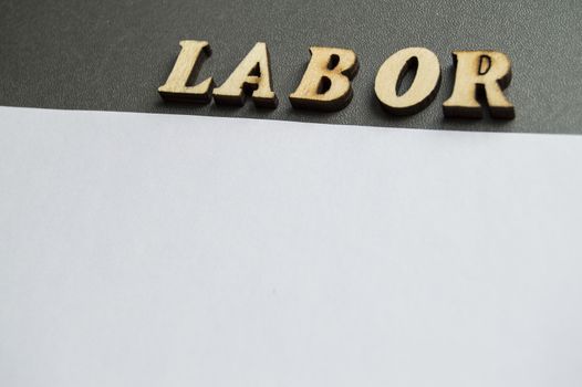 The word labor written in wooden letters to celebrate labor Day in may. Ready design layout for advertising with empty space for text.