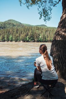 Woman having rest on river coast at the Altai mountain