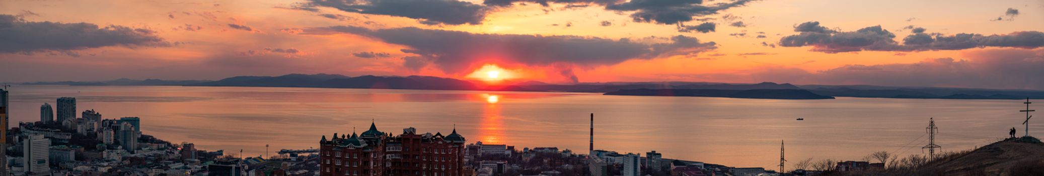 View of the city of Vladivostok from the hill eagle's nest . Sunset. The sky is orange and pink. Sea and city at sunset.