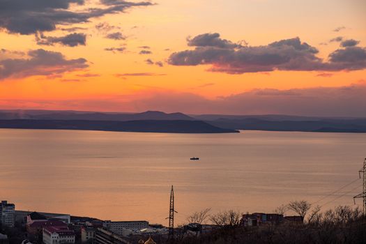 View of the city of Vladivostok from the hill eagle's nest . Sunset. The sky is orange and pink. Sea and city at sunset.